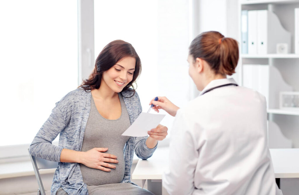 Quels sont les symptômes d'un cerclage qui lâche ? 9 Médecin rassurant une femme enceinte lors d'une consultation, expliquant les symptômes d'un problème de cerclage.
