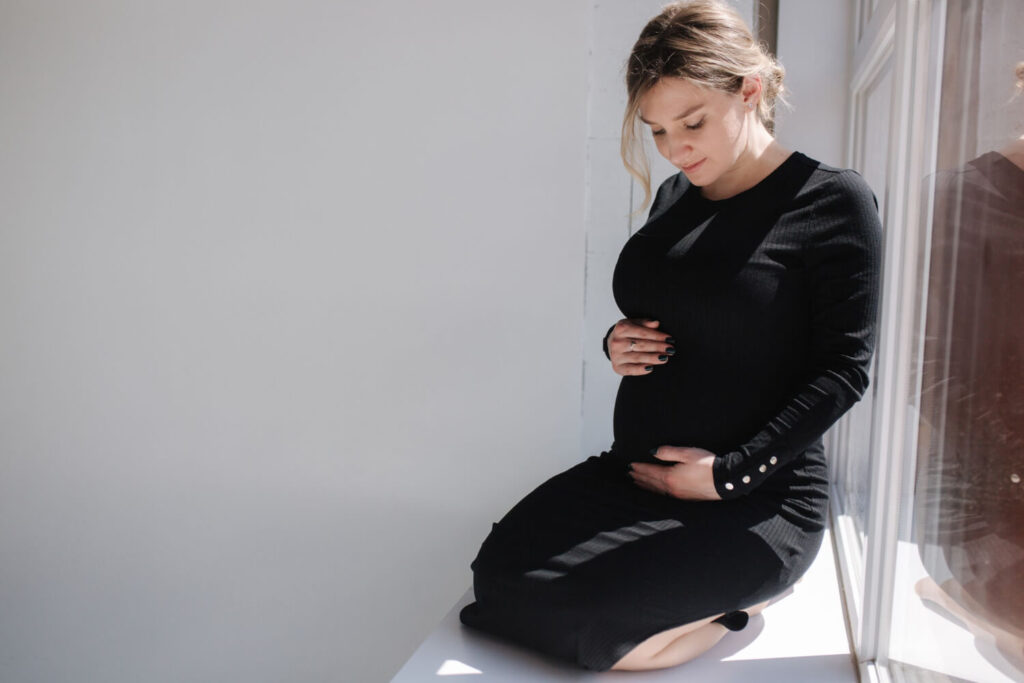 Femme enceinte tenant son ventre en observant les mouvements de son bébé