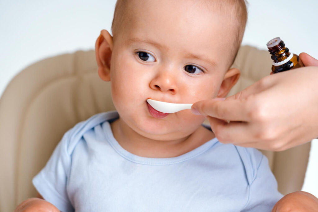 bébé qui prend une cuillère de sirop de Calmosine, un traitement contre les colliques