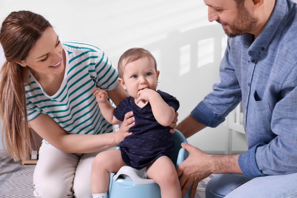 Bébé propre à 1 an : mythe ou réalité ? 2 Parent souriant à un bébé de 1 an assis près d'un pot, illustrant l'apprentissage de la propreté précoce.