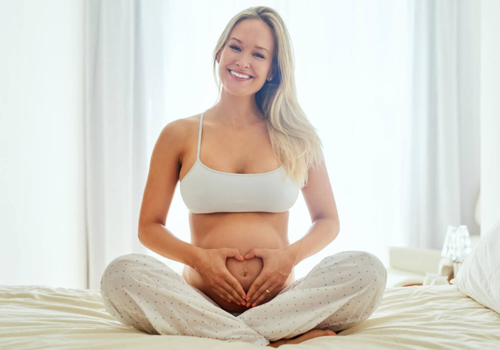 Femme enceinte de 5 mois, souriante et en bonne santé, illustrant la prise de poids normale de 10 kg pendant la grossesse.