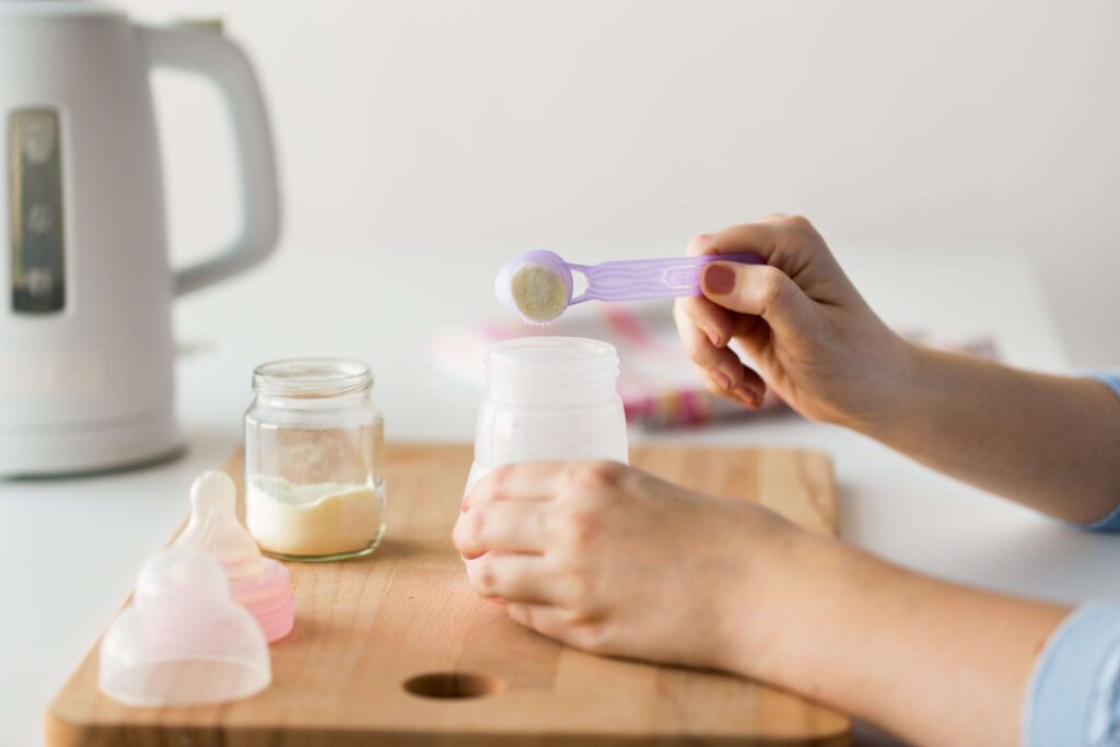 Mettre une dose de lait en plus dans le biberon : DANGER 2 Main d'une femme préparant un biberon