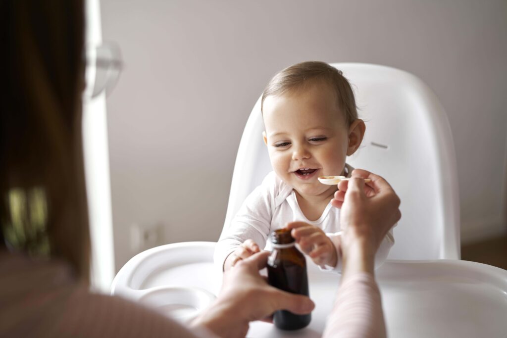 Bébé prenant un médicament avec une cuillère donnée par sa maman