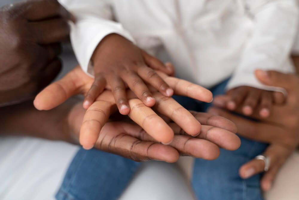 La naissance d'un bébé métis : à quoi s'attendre ? 4 Mains de deux parents, l'une à la peau blanche et l'autre à la peau noire, tenant les petits pieds de leur bébé métis.
