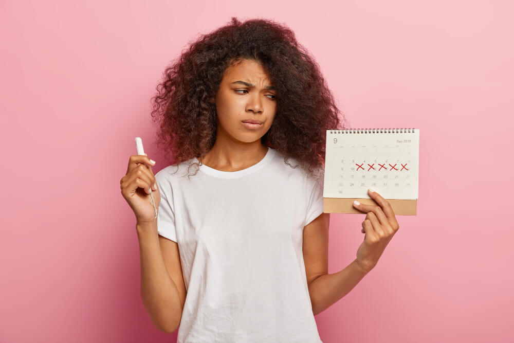 Saignement vaginal après être allée à la selle : quelles sont les causes ? 5 Femme consultant un calendrier, l'air soucieux, notant un saignement en dehors de ses règles.