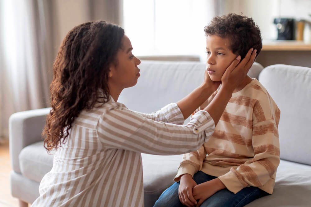 Mon fils de 9 ans est insupportable : que se passe-t-il ? 3 Mère et son fils de 9 ans en pleine discussion tendue dans un salon, illustrant un conflit parental.
