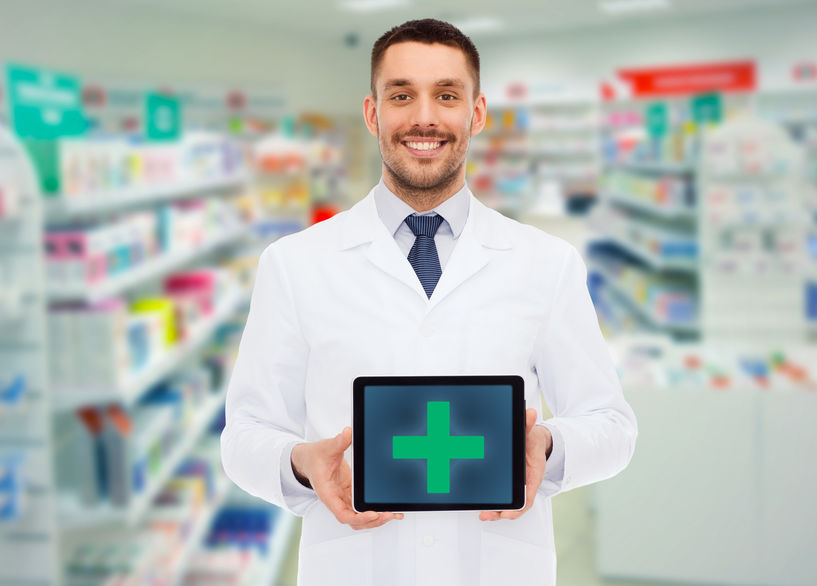 medicine, pharmacy, people, health care and pharmacology concept - smiling male doctor showing tablet pc computer with cross symbol on screen over drugstore background