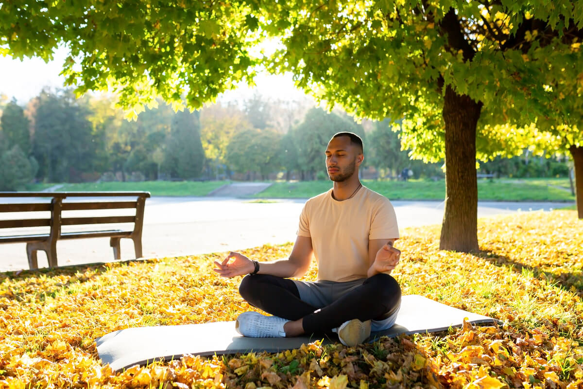 Une personne en méditation dans un parc paisible illustrant l'équilibre mental et physique.