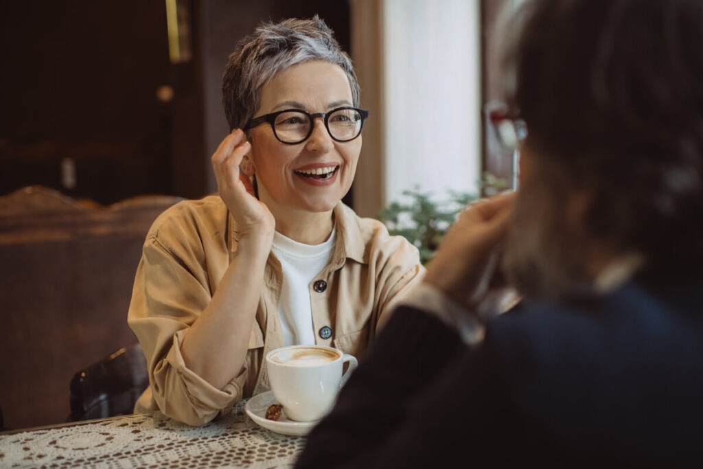 Une personne souriante en pleine conversation, retrouvant un confort d'écoute grâce à une solution auditive invisible.