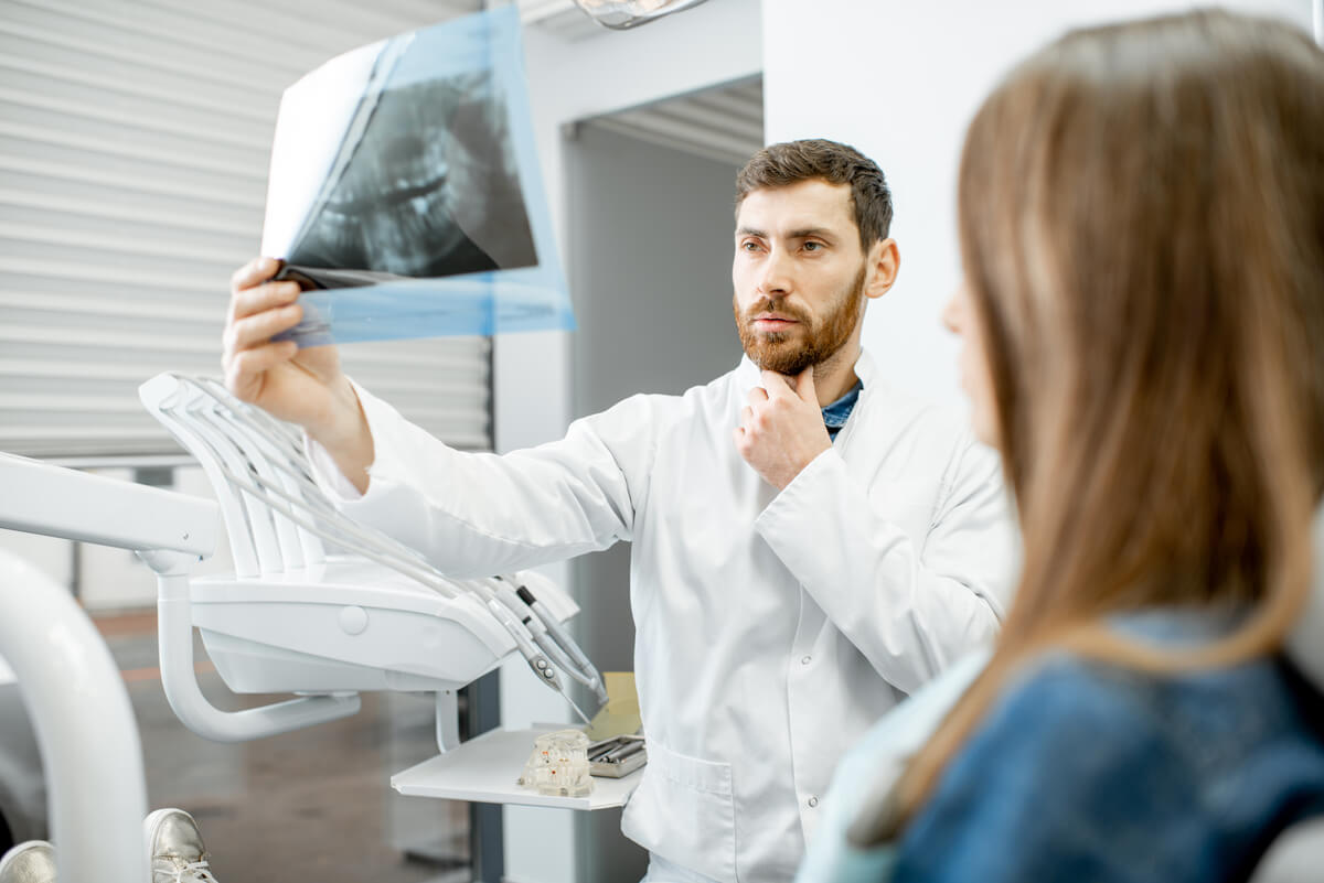 Chirurgien-dentiste analysant la radiographie panoramique de la mâchoire d'un patient souffrant
