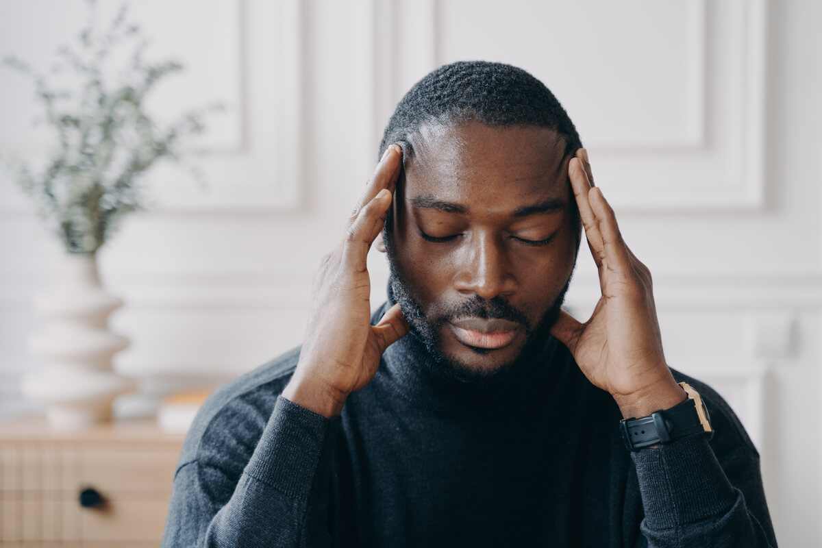 Homme se tenant la tête avec angoisse ressentant un spasme ou une décharge neurologique