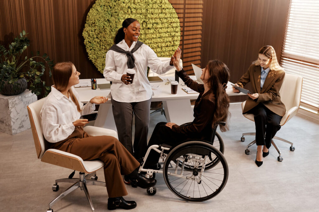 Une équipe de travail diversifiée en réunion, incluant un collaborateur en fauteuil roulant, symbolisant l'inclusion réussie.