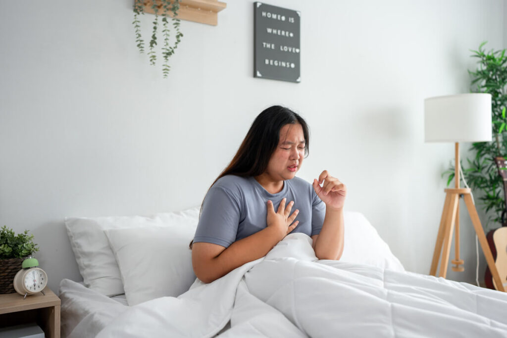 Personne se réveillant en sursaut avec une main sur la poitrine illustrant un malaise au coucher.