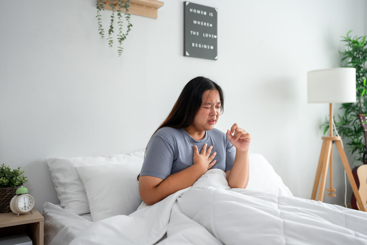 Personne se réveillant en sursaut avec une main sur la poitrine illustrant un malaise au coucher.