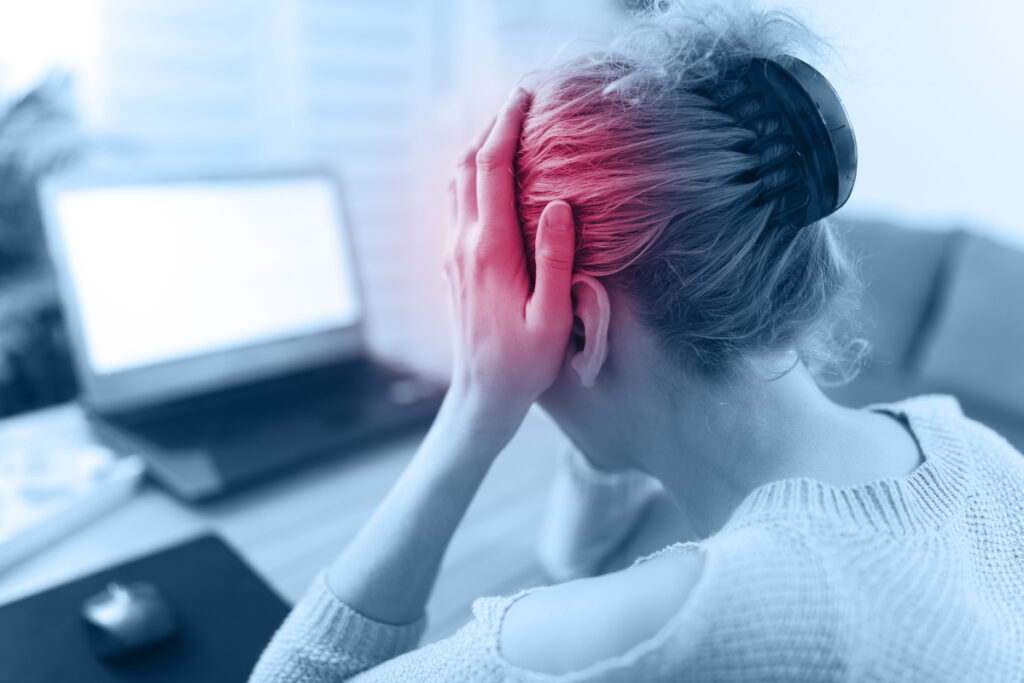 Une personne se massant les tempes devant un écran, illustrant les maux de tête liés à une correction inadaptée.