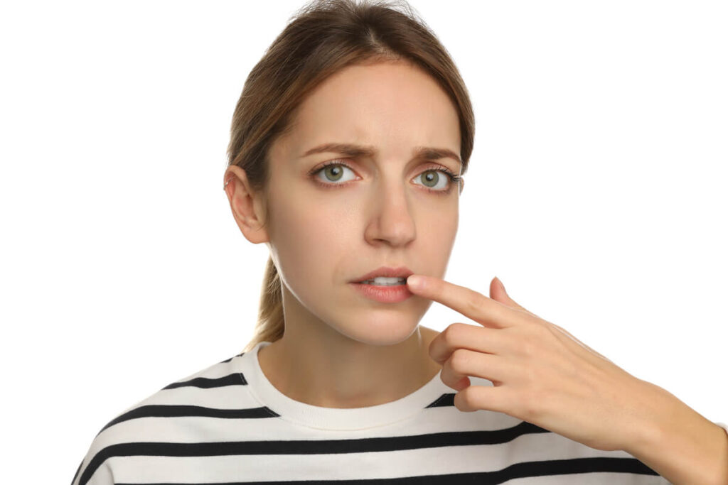 Femme se pinçant légèrement les lèvres et la langue, illustrant la retenue verbale et le secret
