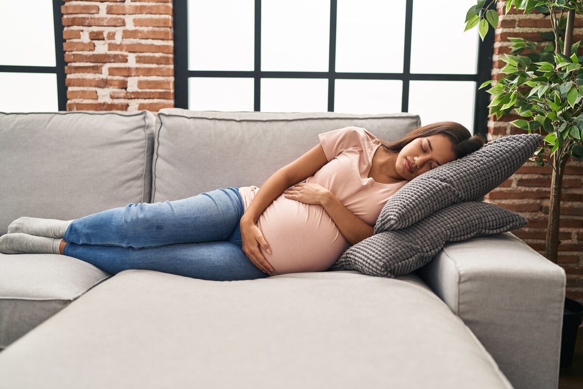 Femme enceinte alitée dormant sur le côté gauche avec un coussin d'allaitement entre les jambes