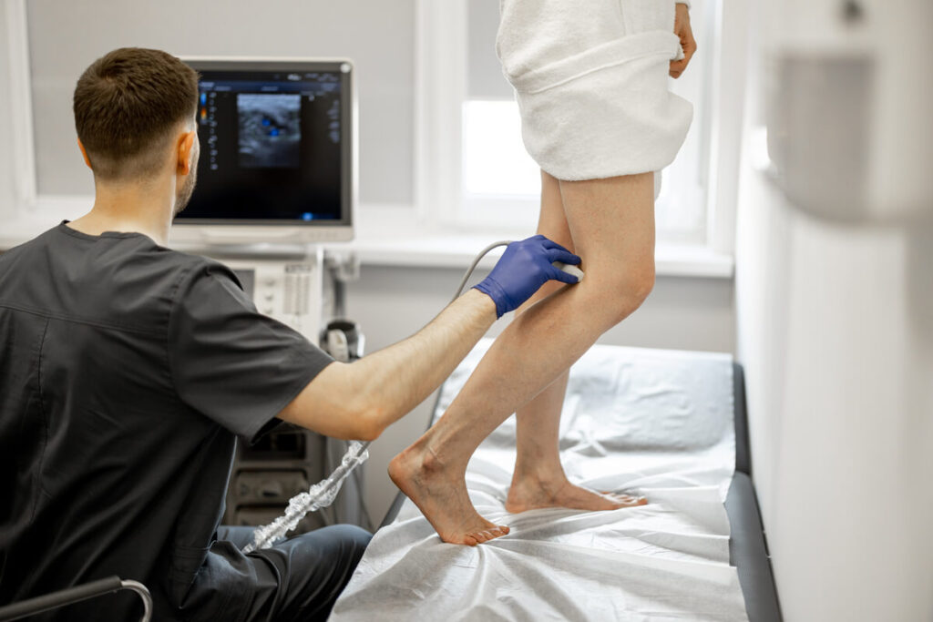Un médecin angiologue examinant la circulation sanguine des jambes d'un patient lors d'une visite de contrôle.