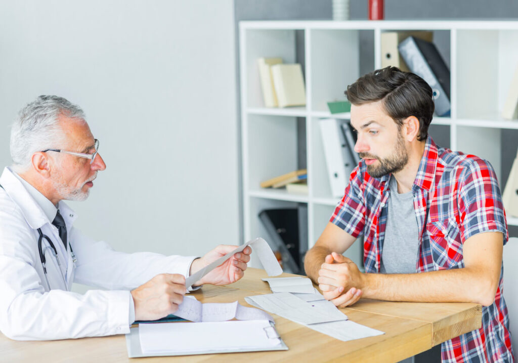 Un médecin expliquant les résultats d'un bilan hépatique à un patient lors d'une consultation d'oncologie.