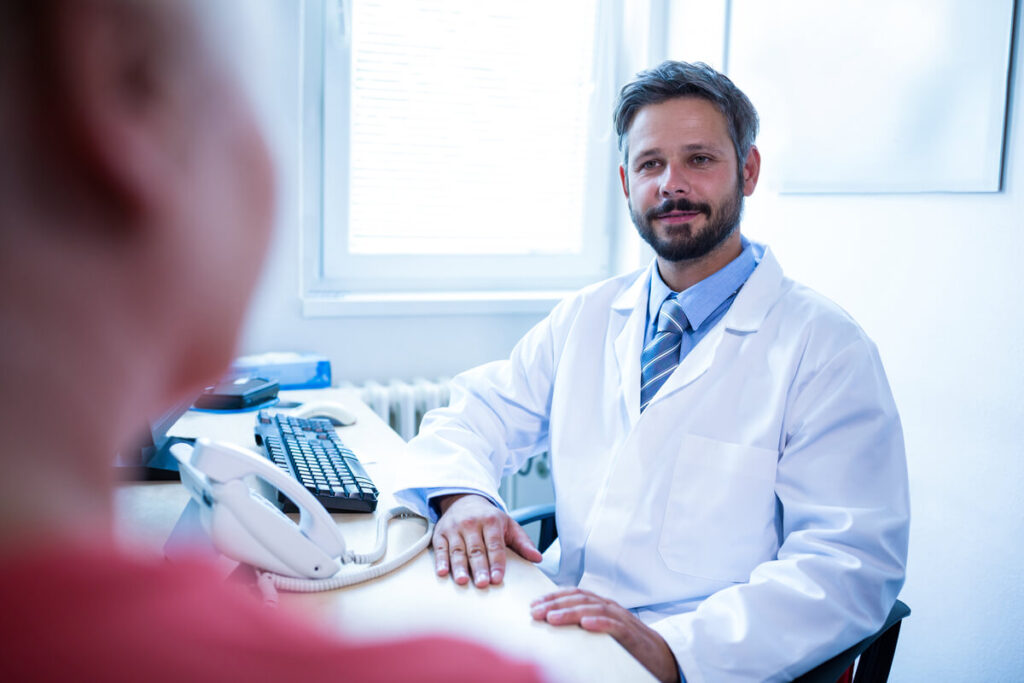 Un médecin urologue expliquant le déroulement d'une posthectomie à un patient adulte lors d'une consultation.