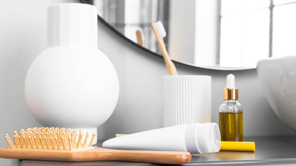 Du dentifrice blanc déposé sur une brosse à dents en bambou dans une salle de bain claire.