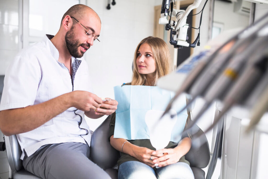 Un dentiste bienveillant expliquant calmement les étapes du soin à un patient adulte pour apaiser sa peur.