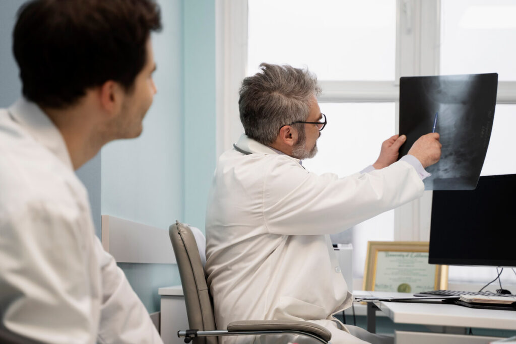 Un médecin radiologue analysant les disques lombaires d'un patient sur un écran d'imagerie.
