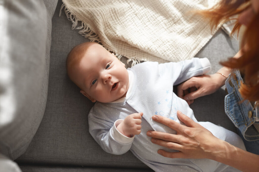 Bébé a mal au ventre depuis la diversification : solutions et explications simples 3 Les mains douces d'un parent massant délicatement le ventre d'un nourrisson pour soulager ses coliques.