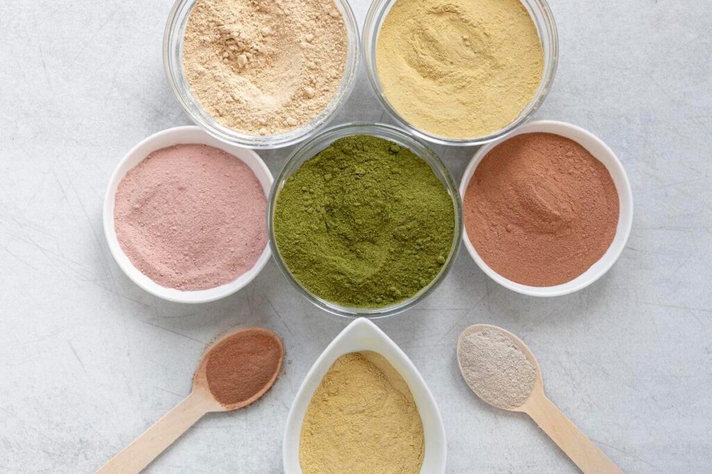 Coloration vegetale bio : choisir une formule capillaire saine et certifiee 3 Différentes poudres de plantes tinctoriales comme le henné et l'indigo utilisées pour une coloration végétale bio.