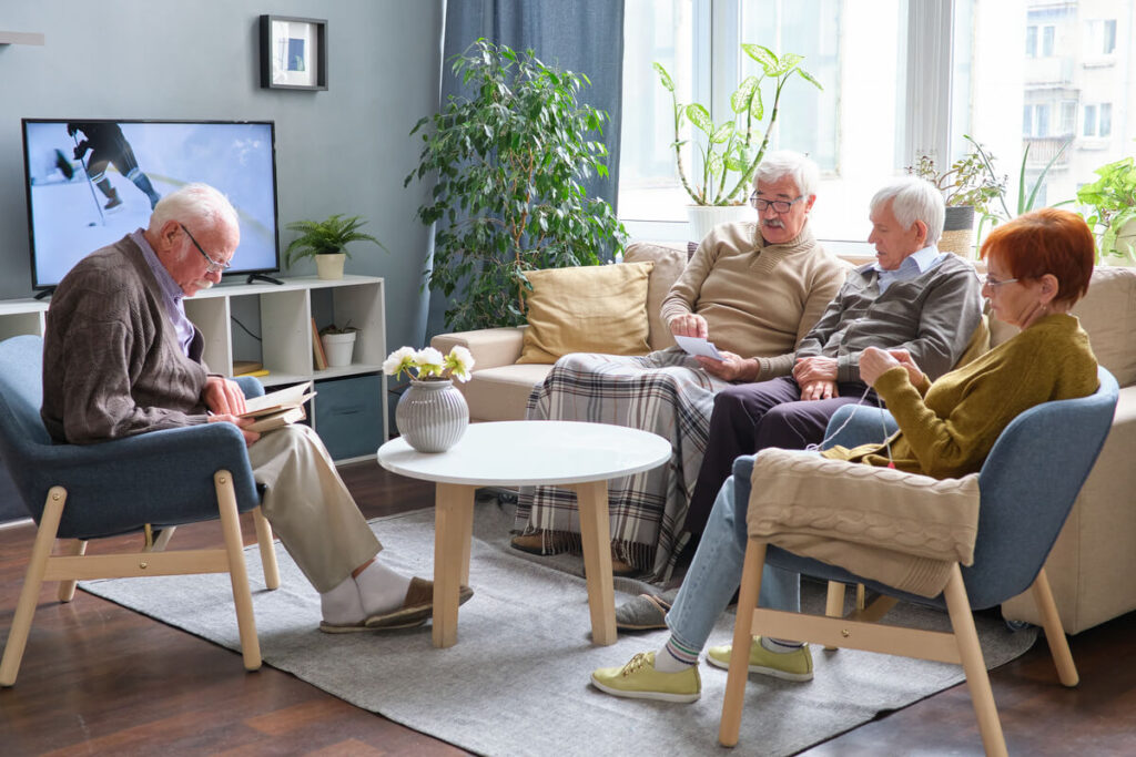 Des résidents seniors échangeant chaleureusement dans le salon commun d'une résidence services moderne.