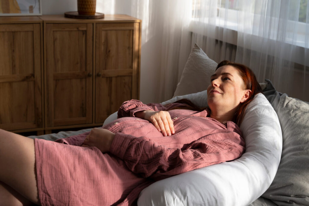 Douleur IVG vs accouchement : peut-on vraiment les comparer ? 5 Une femme allongée sereinement chez elle avec une bouillotte chaude sur le ventre.