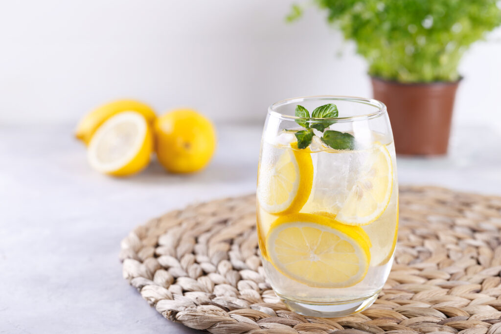 Un grand verre d'eau fraîche avec des rondelles de citron pour illustrer une hydratation saine et protectrice.