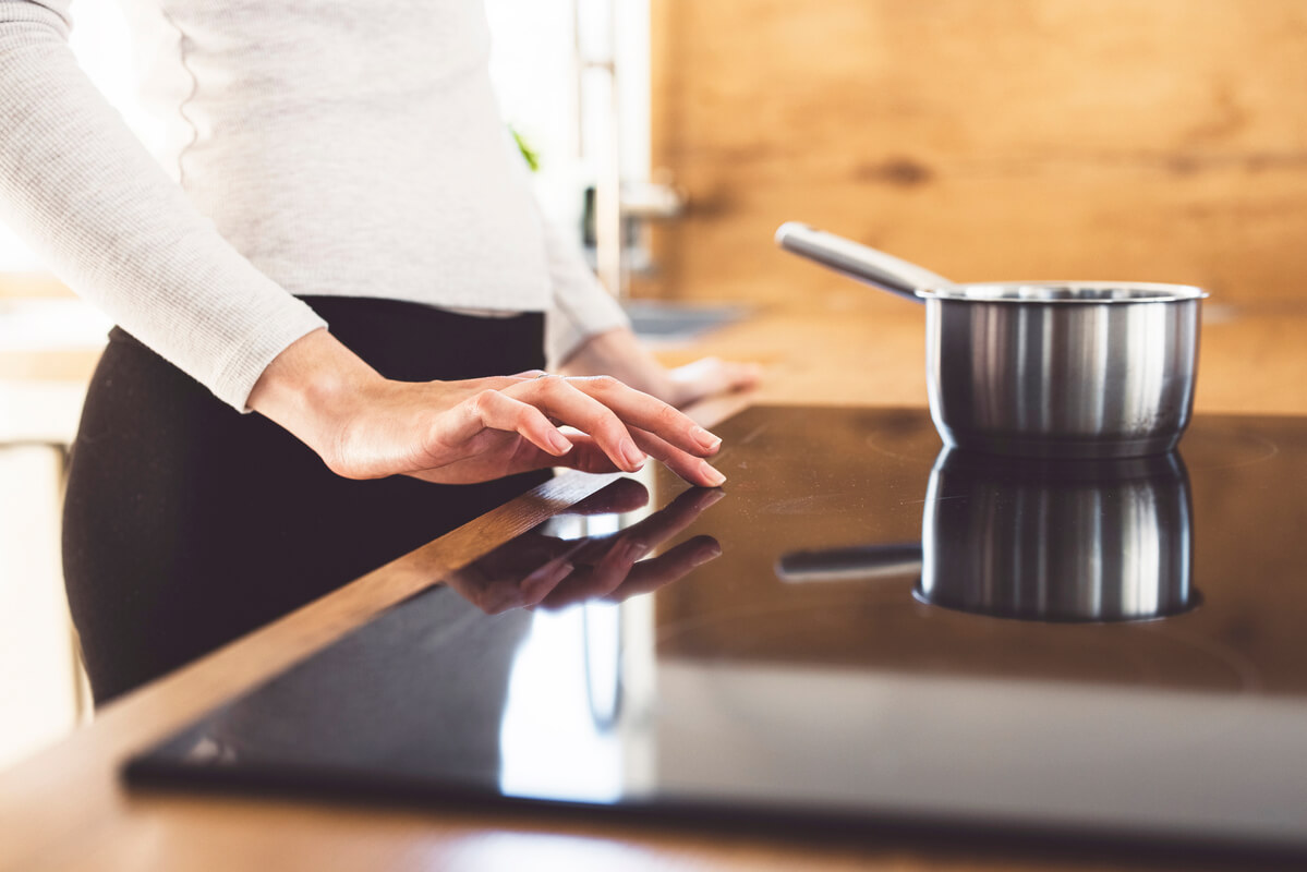 Une personne cuisinant sur une table de cuisson moderne dans une cuisine intégrée.
