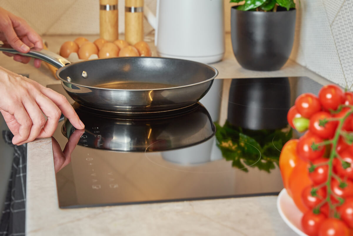 Une personne cuisinant sur une plaque à induction moderne avec des casseroles adaptées en acier inoxydable.