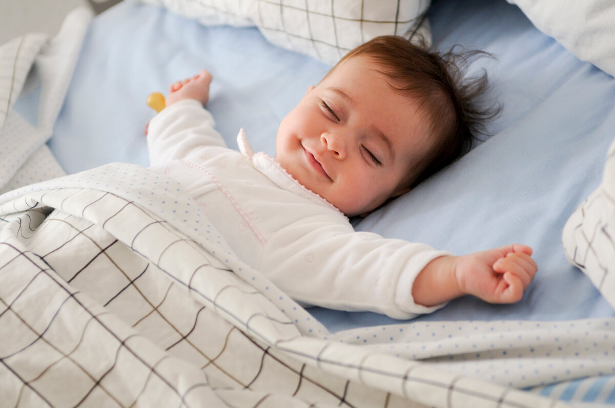Un bébé paisiblement endormi en couche sur un drap léger pendant une sieste d'été.