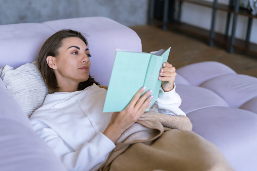Un patient au repos lisant un livre, évitant tout effort physique pour soulager sa cage thoracique.