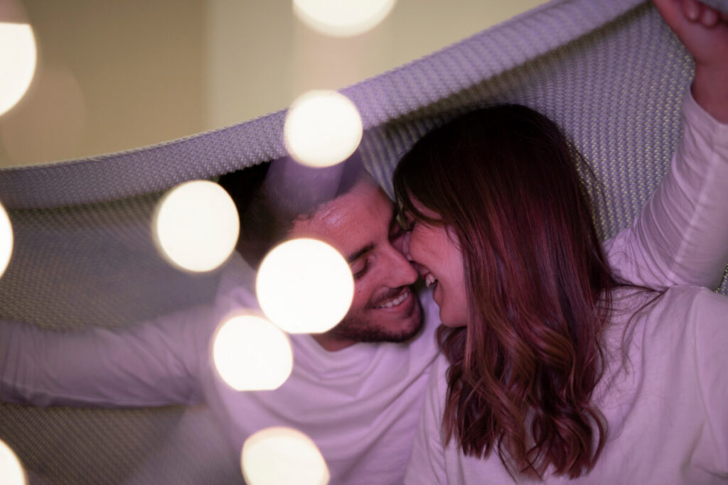 Plaisirs érotiques : l'art d'éveiller vos sens au quotidien 2 Couple partageant un moment de complicité sensorielle dans une pièce aux lumières douces.