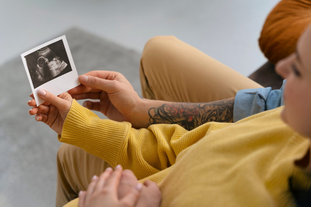Taux HCG fille ou garçon : peut-on prédire le sexe du bébé grâce à la prise de sang ? 3 Une future mère souriante regardant l'écran d'une échographie obstétricale chez son médecin.