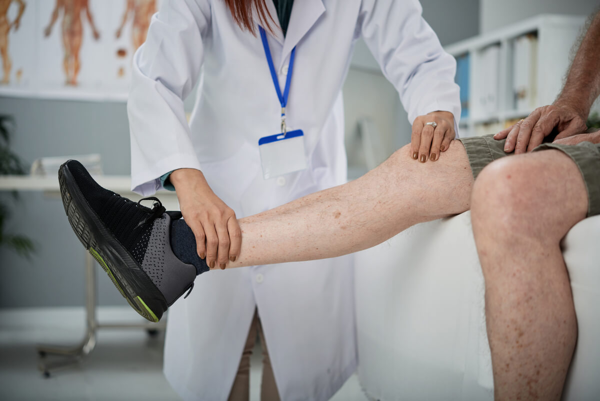 Un professionnel de santé examinant une bosse douloureuse sur le tibia d'un patient.