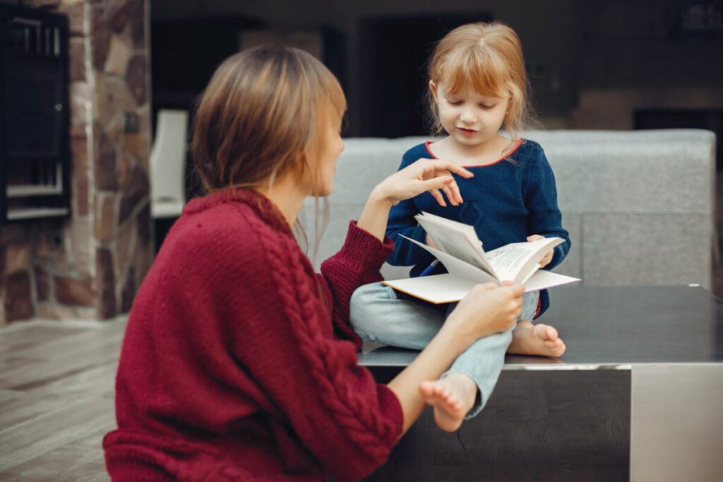 Comment choisir la garde d'enfants idéale pour votre famille ? 3 Une professionnelle de la petite enfance lisant une histoire de conte à un enfant dans son salon.