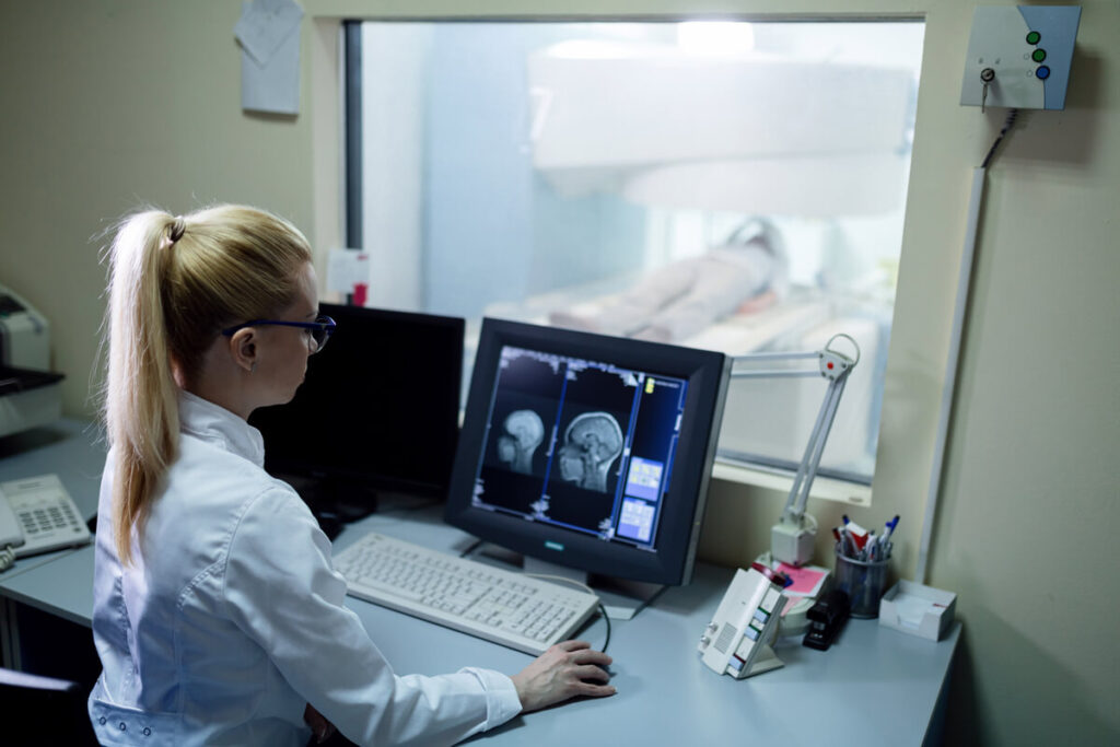 Atrophie cortico-sous-corticale et vertiges : causes et prise en charge 2 Médecin analysant les coupes d'une IRM cérébrale montrant une atrophie.