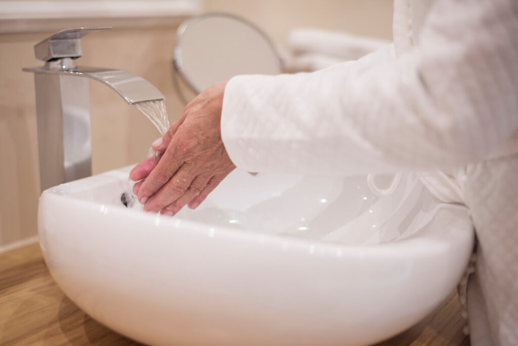 Retour à la maison après un traitement à l'iode radioactif : consignes et précautions 3 Un patient se lavant soigneusement les mains au savon sous le robinet de la salle de bain.