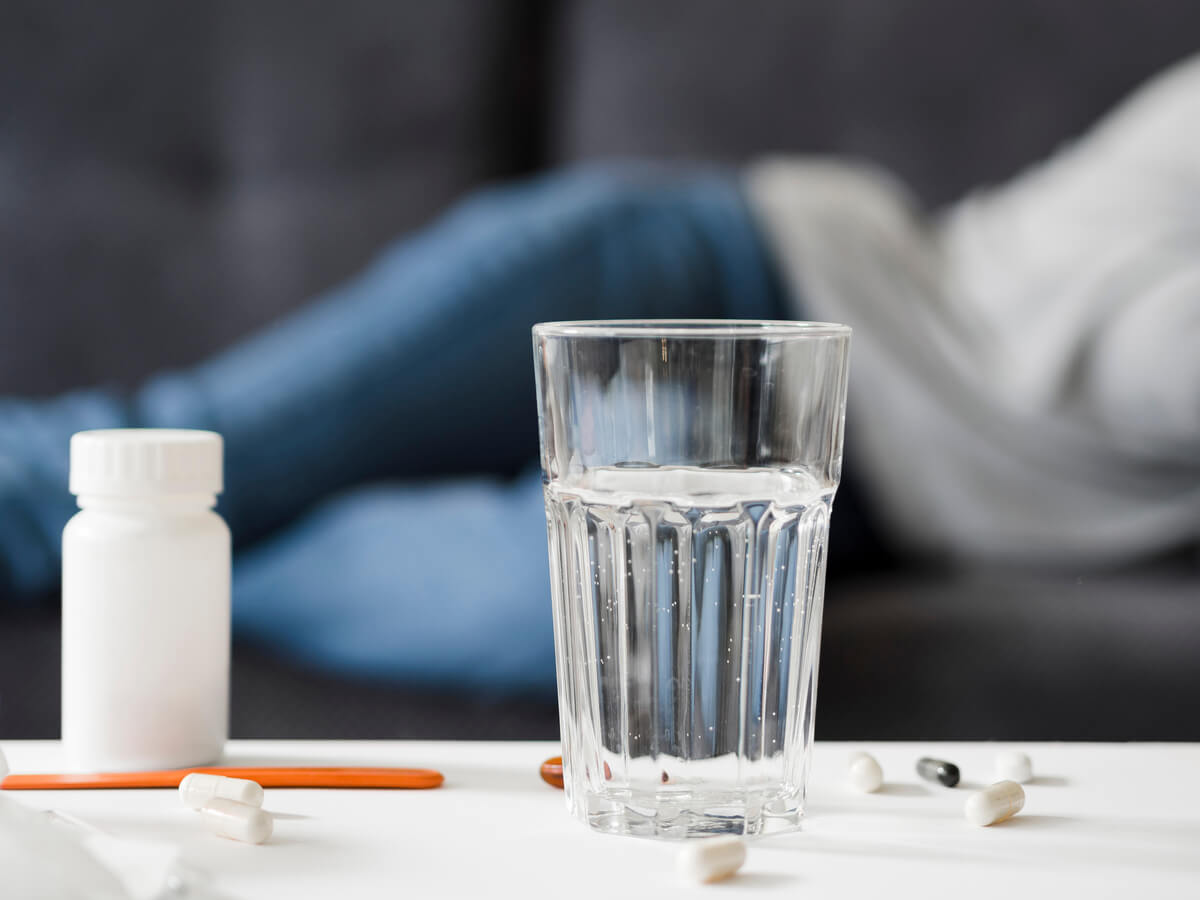 Des comprimés médicaux disposés à côté d'un verre d'eau sur une table de chevet.