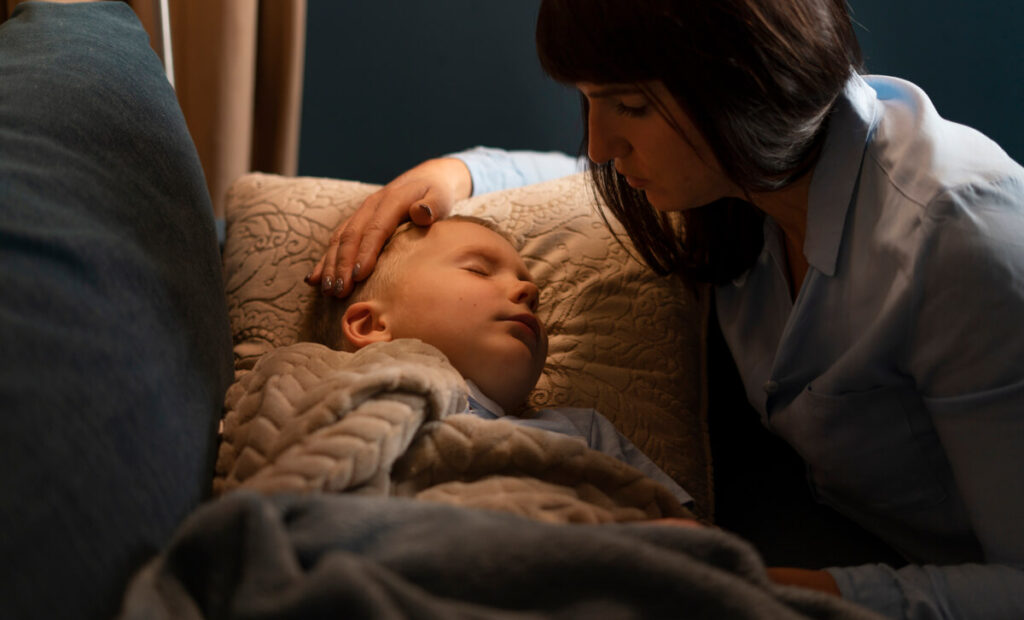 Une mère réconfortant doucement son enfant de 3 ans dans son lit avant de dormir.