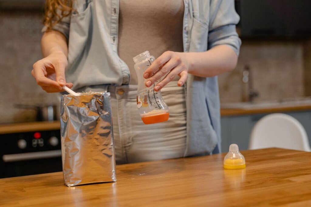 Blédine 4 mois le soir : conseils, dosage et diversification de bébé 3 Une cuillère versant des céréales infantiles instantanées dans un biberon de lait propre.