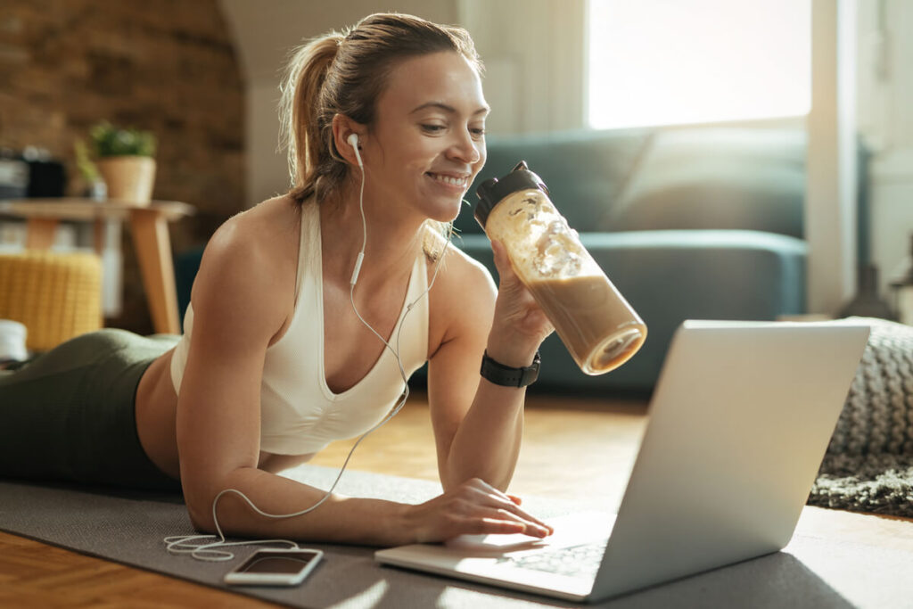 Une personne versant une dosette de poudre de protéine végétale bio dans un shaker de sport.