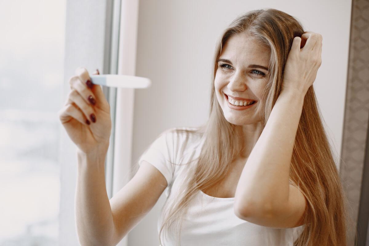 Une femme tenant un test de grossesse positif dans ses mains, soulagée.