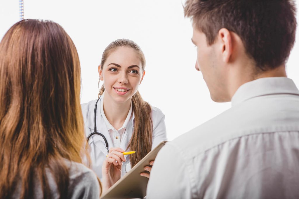 Médecin généticien expliquant les modes de transmission d'un réarrangement chromosomique à un couple.