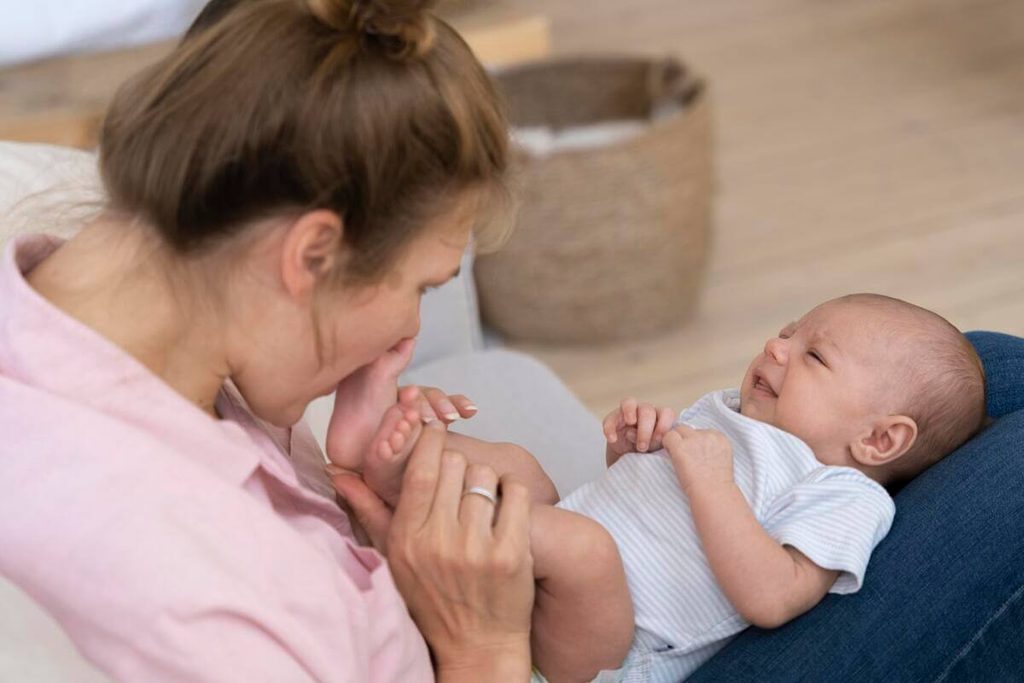 Parent réalisant un massage circulaire doux sur le ventre de son bébé pour évacuer les gaz.