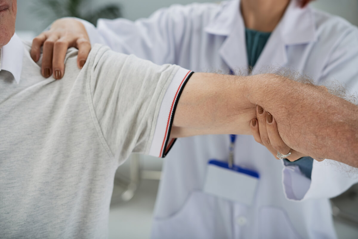 Médecin du travail examinant la mobilité du bras d'un salarié après une chirurgie de l'épaule.